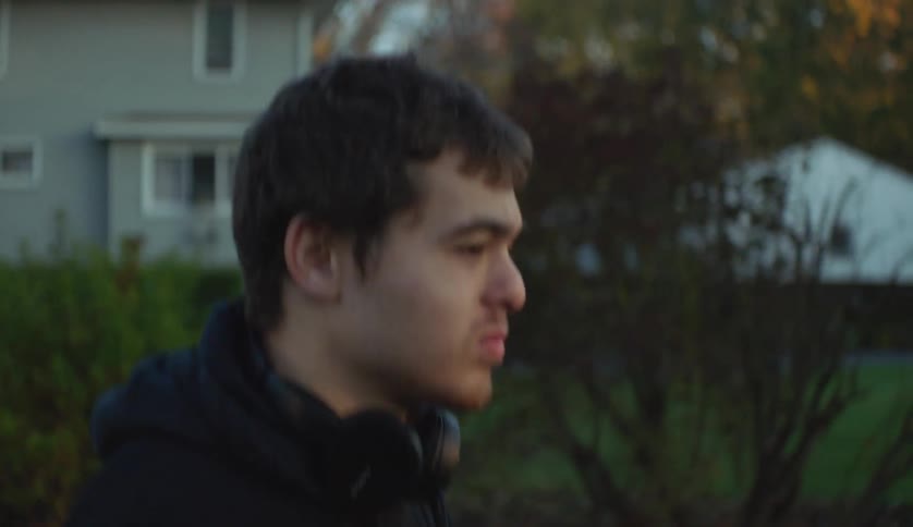 A young man is walking outside in a small town