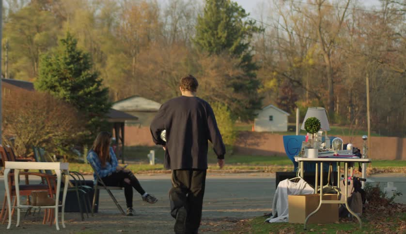 Young man walks away from a garage sale with a disco ball under his arm