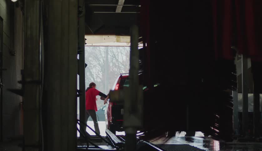 An employee is washing the car as it goes through the carwash
