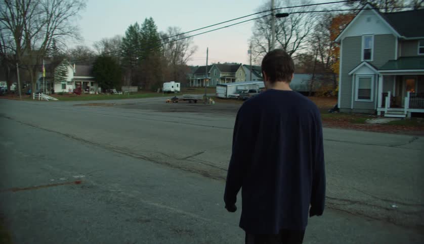 Young man wearing a long sleeve shirt walks around the neighborhood