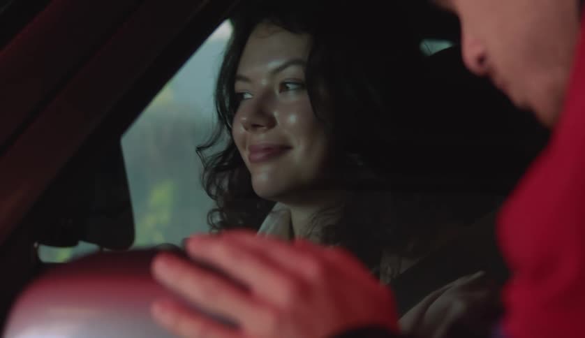Female driver sitting in car smiles as worker wipes side mirror