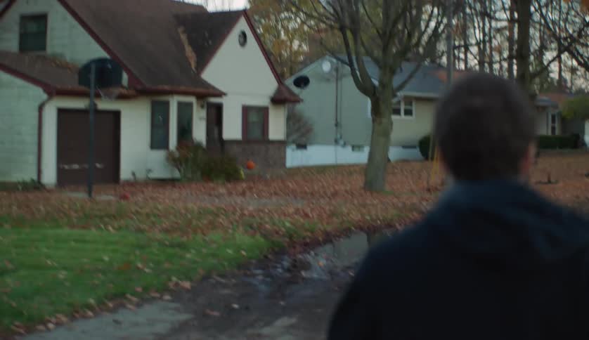 A young man is walking outside in a small town