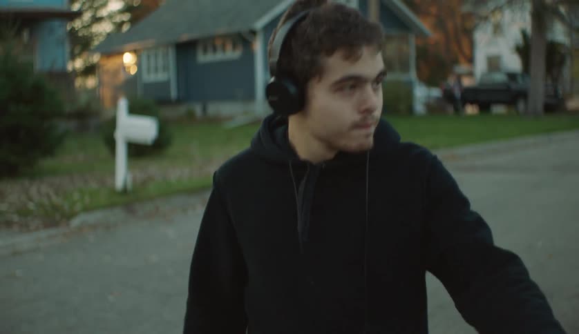 A teen is walking through a neighborhood during the spring