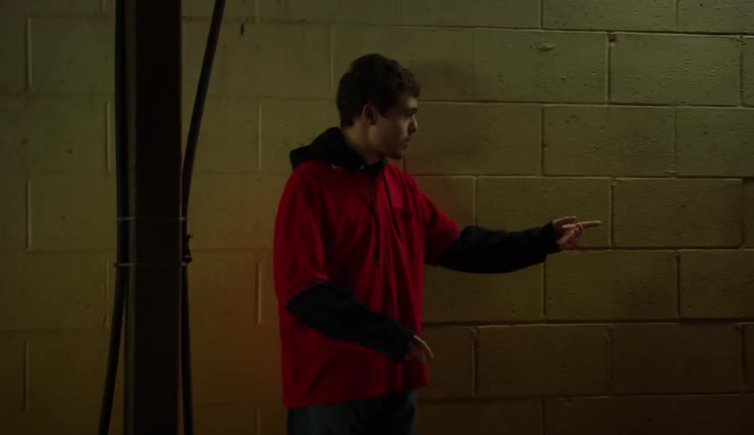A man wearing a red shirt walking and then getting something from another man walking