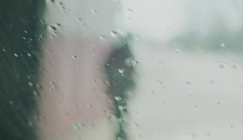 Silhouette of a man reclined on a wall seen from the interior of a car coming out of a carwash