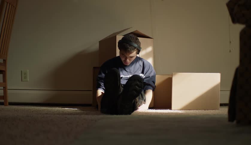 A young man is sitting on the ground and listening to music