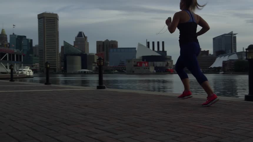 A woman is jogging near the water at sunset