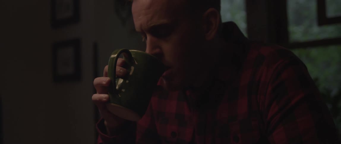A man slowly lifts a mug and drinks from it