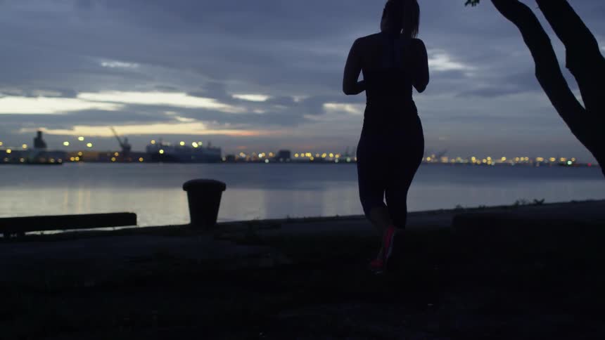 A woman walks towards the water at sunset
