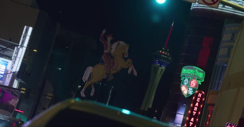 A vehicle drives through a lit up downtown