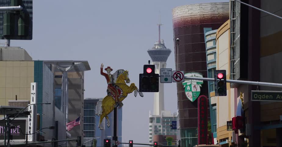 Cars traveling on an urban street with a cowboy on a horse statue in the distance