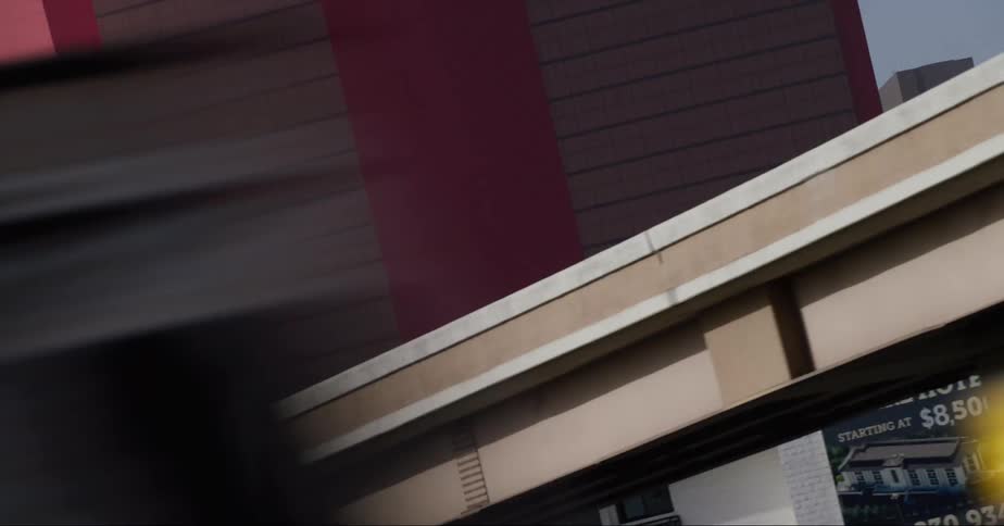 Vehicles drive along and under overpass near buildings