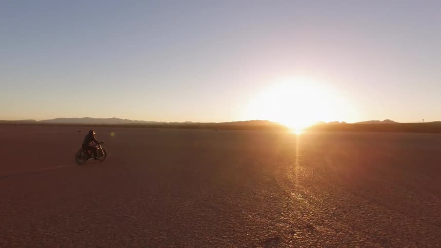 A person drives a motorcycle across the desert