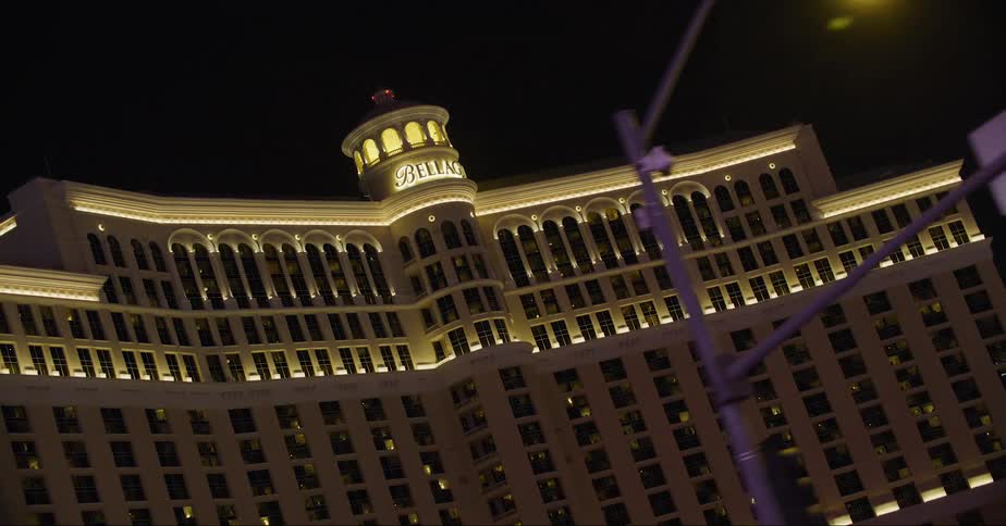 People stand near busy intersection near bellagio hotel and casino at night