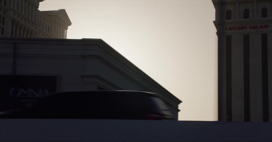 The vehicle drives past the buildings