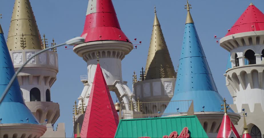 A vehicle drives by a business and tall colorful towers in an amusement park