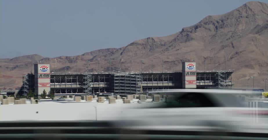 Highway passes large stadium sitting at base of mountain on clear day