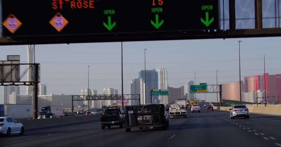 Many cars travel along a freeway on the way to a large city