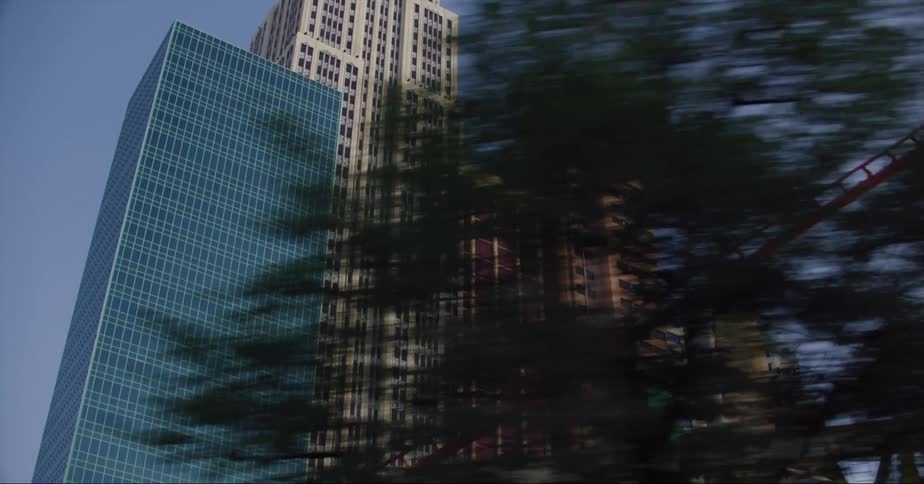 Facade of tall skyscrapers in the city skyline at daytime seen from a moving vehicle
