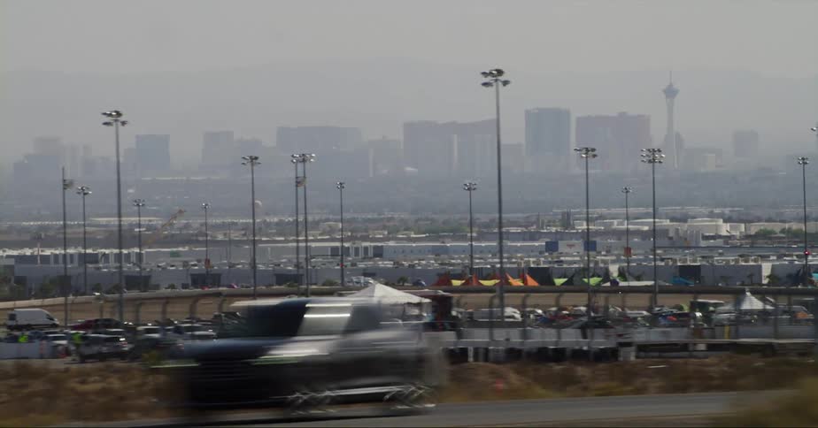 Vehicles move along busy highway passing stadium with fog covered skyline on the horizon