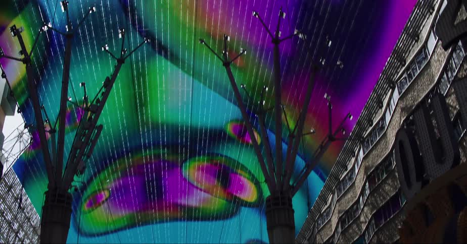 Colorful display plays about ceiling of structure next to building