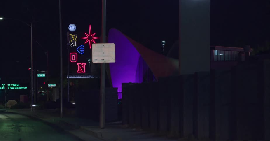 Cars drive past the neon signs