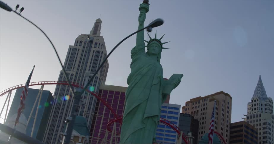 A bus passes by a smaller statue of liberty statue in a city