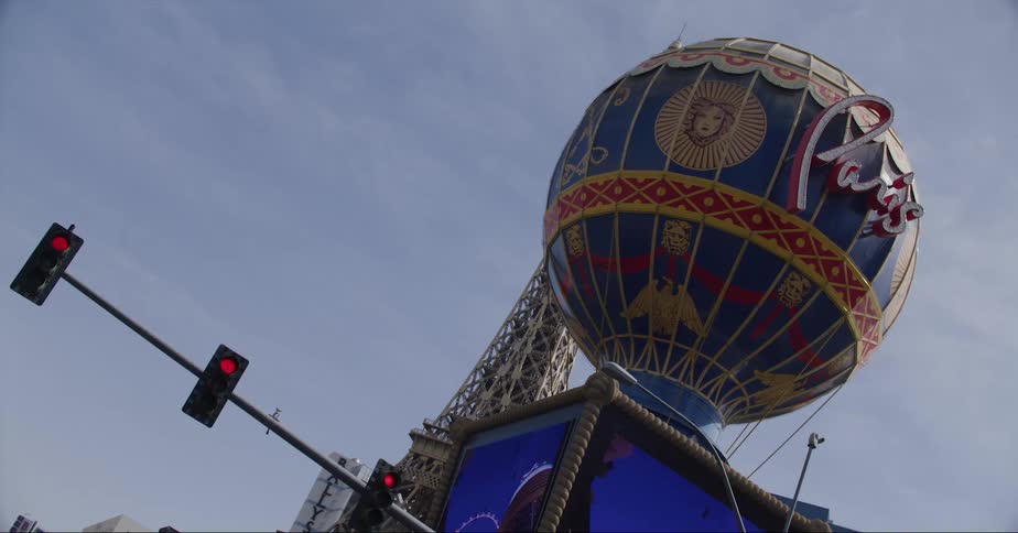 Paris hot air ballon on top of a marquee next to a stop light on a partly cloudy day