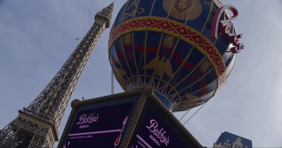 An airplane flies over a tower and hotels in a city