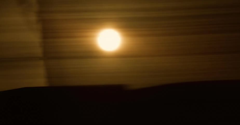 Bright yellow sun shines behind a screen seen from a moving vehicle