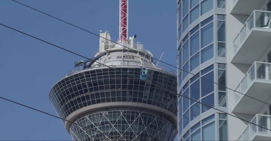 A tower with a ride on top behind an apartment building in a city