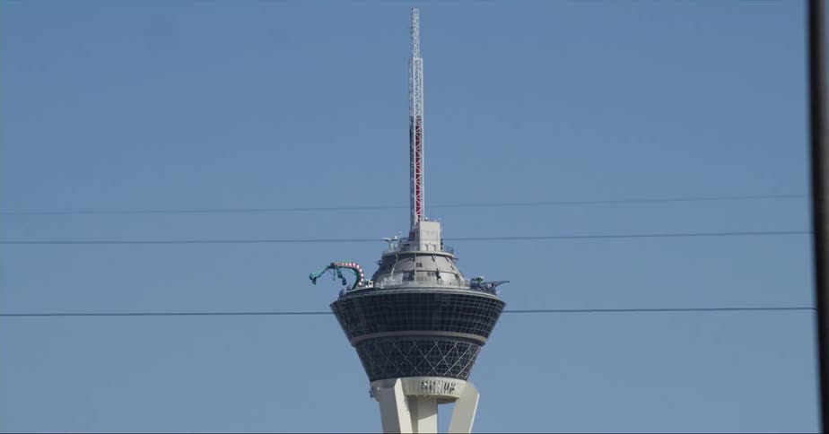 Machine rotates arms at top of tower standing above power lines