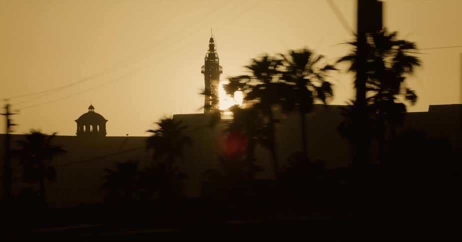 Sun shines from red sky silhouetting buildings