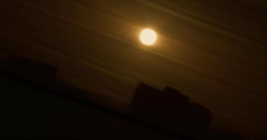 Sun shines in a yellow sky over the city skyline seen from a moving vehicle