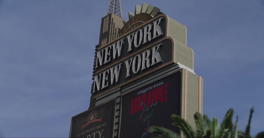 The top portion of new york new york hotel surrounded by signs
