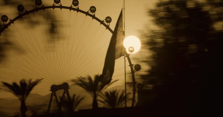 Amusement park and ferris wheel are silhouetted against the sun