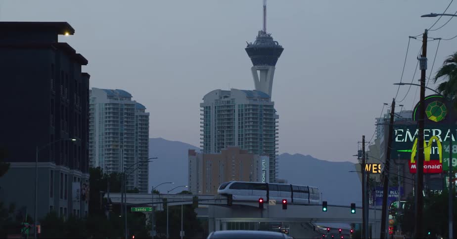 The strat tower and high rise buildings seen from vehicle driving on highway at dusk in las vegas