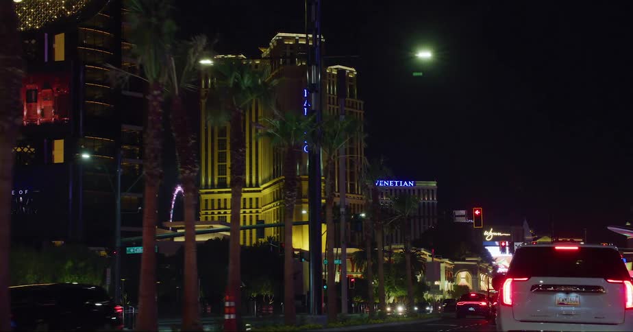 Pedestrians cross street as traffic on las vegas strip stop at intersection near casinos at night