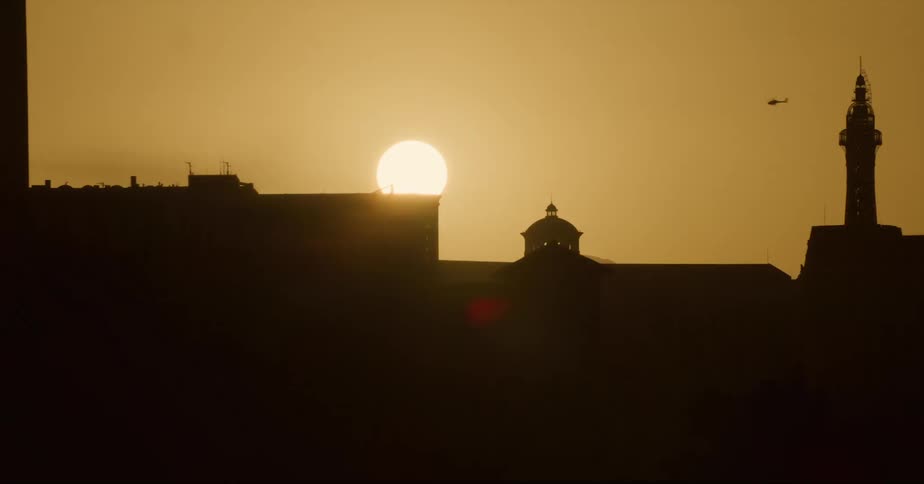 Sun shines over the city skyline at evening seen from a moving vehicle