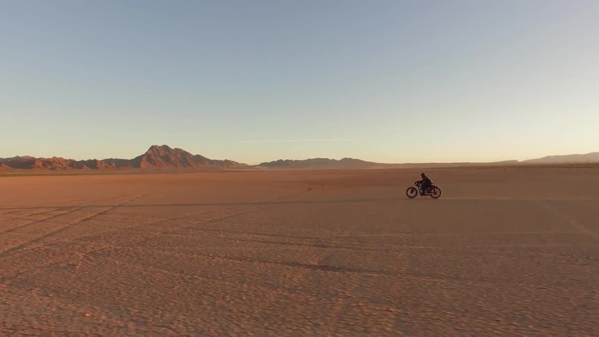 A man speeds through the desert on a motorcycle
