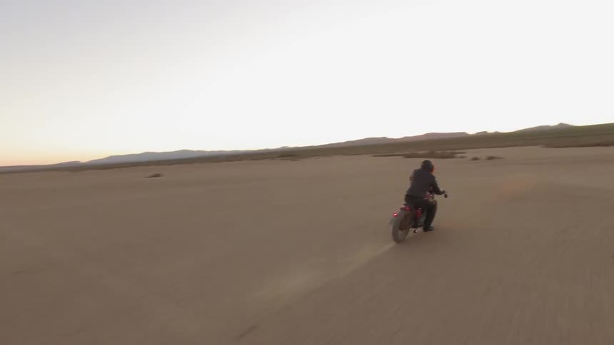 A person rides a motorcycle in the desert