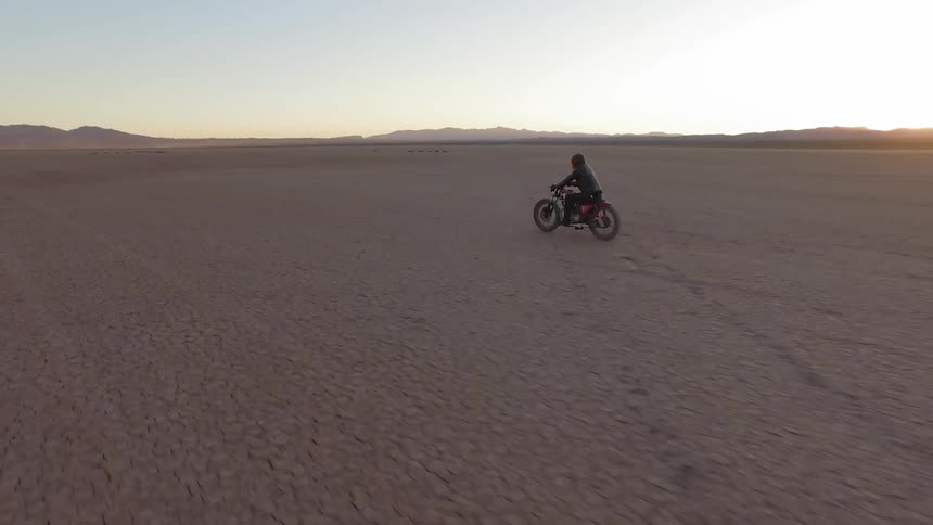 A person rides a motorcycle through the desert