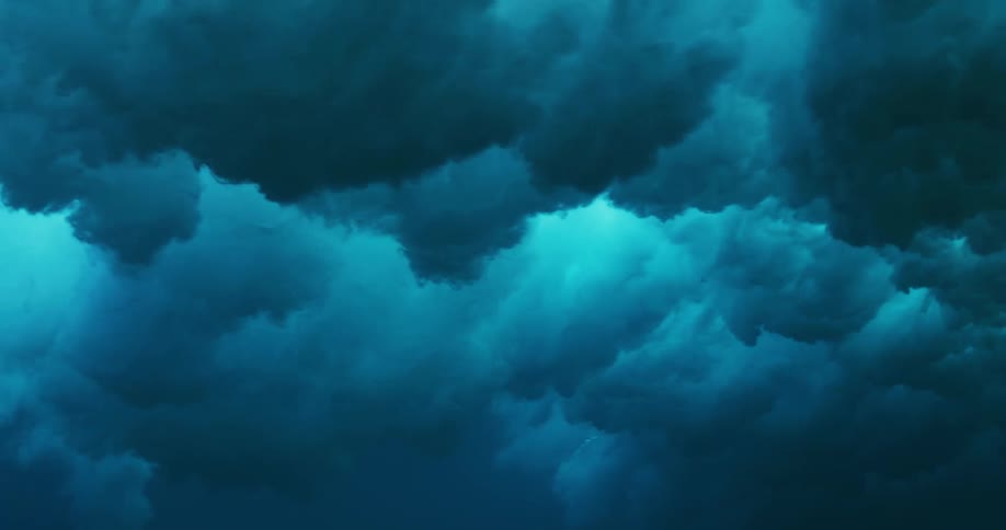 Underwater view of a wave rolling overhead and sunlight reflecting the ripples as water splashes