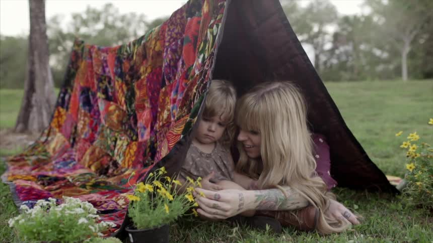 A woman and child examine flowers under a tent