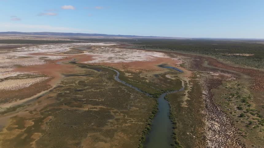 Aerial view of a river flowing intto a salt marsh in the plains at daytime