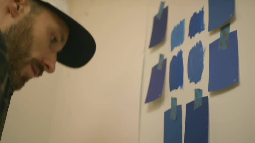 Man puts paint samples on wall to select paint color