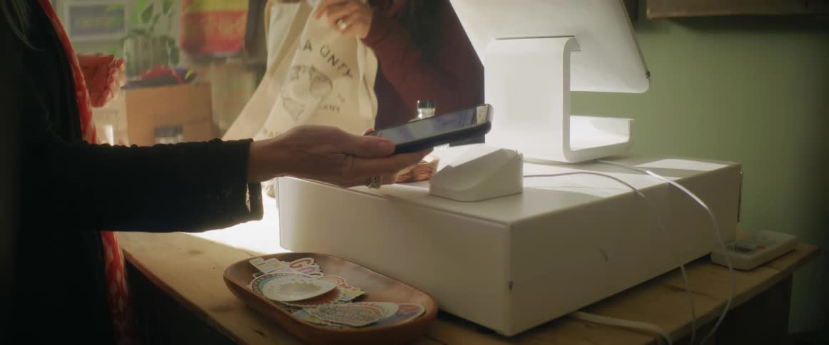 Woman uses her smartphone to pay on a small business
