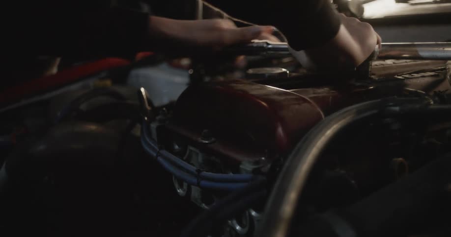 Mechanic uses a wrench while fixing an engine in the garage