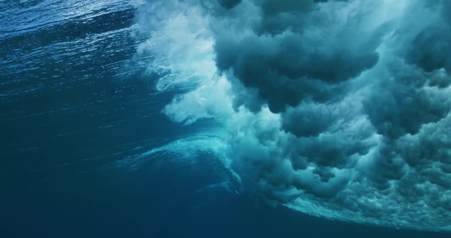 A wave rolls across the ocean during the day