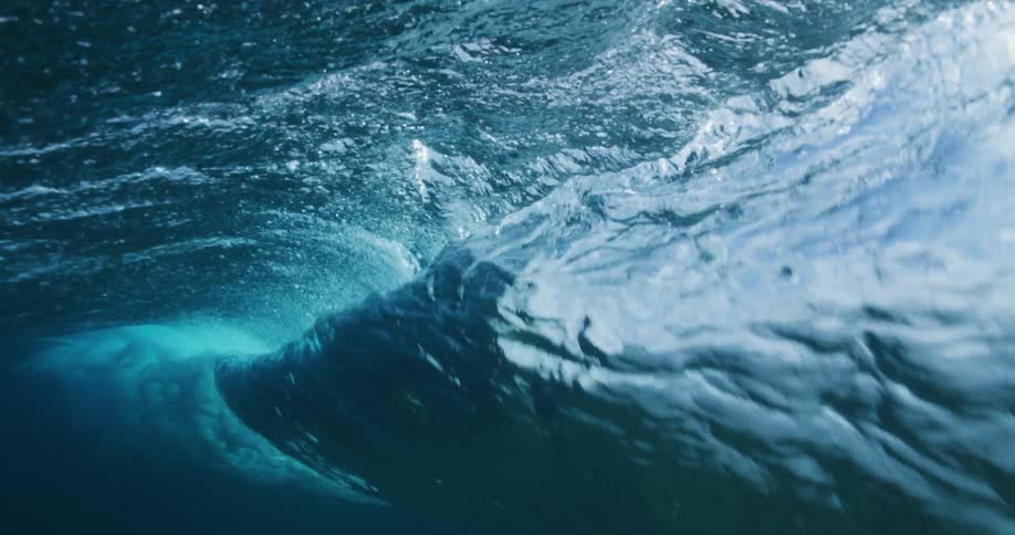 Water ripples and waves as sunlight shines underwater as a wave moves overhead